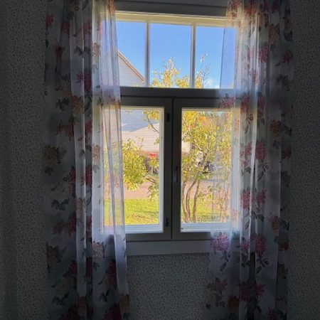 Makuuhuoneen verhot ja niihin sopiva tapetti vanhassa talossa.