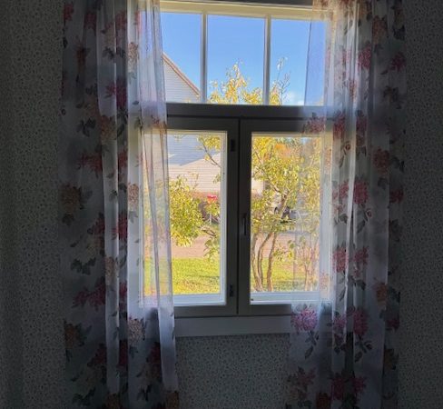 Makuuhuoneen verhot ja niihin sopiva tapetti vanhassa talossa.