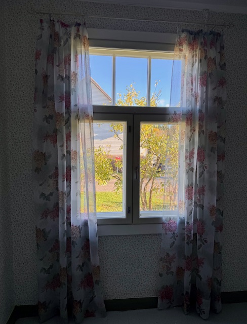 Makuuhuoneen verhot ja niihin sopiva tapetti vanhassa talossa.